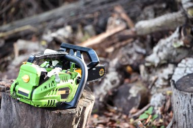 Elektrikli testere. Elektrikli testereyle odun kesiyor, kışa yakacak odun hazırlıyor, kırsal alanda sıkı çalışıyor. Elektrikli testere kütüğün üzerinde duruyor, odunların odun kesilmesi gerekiyor. Yakın plan. Benzin aracı