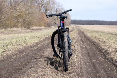 Kyiv bölgesi, Ukrayna, 03.04.2021 motorun arka tekerleği. Dağ bisikleti tarlada bir yolda duruyor. Bisiklet konsepti, tamir ya da bozulma, spor, açık hava aktiviteleri. Bisiklet kötü yolda. Yazı