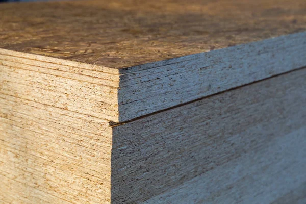 The stack of chipboard is stored in the wholesale warehouse. Selective focus with blurred background, shallow depth of field.