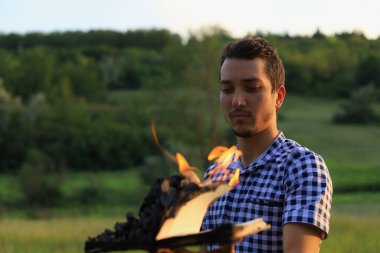 Beyaz Kafkasyalı genç adam ya da yetişkin adam bulanık orman geçmişi üzerine yanan bir kitap okuyor..