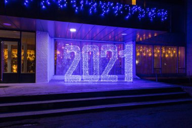 2021 yazıtında, şehir ortamında sokakta soğuk bir tonda çelenk kullanılmış. Soyut yeni yıl veya noel arkaplanı