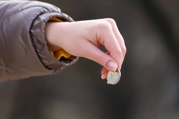 Womans hand and coin. Financial aid and contribution concept