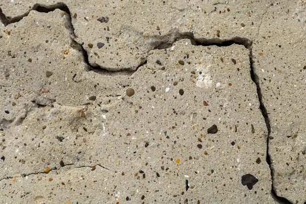 Çatlak beton bir temel tabakasının pürüzlü dokulu yüzeyi.