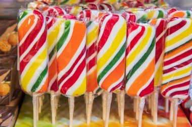 Çubuğun üzerinde parlak çizgili çok renkli şekerler. Şeker dükkanı rafı..