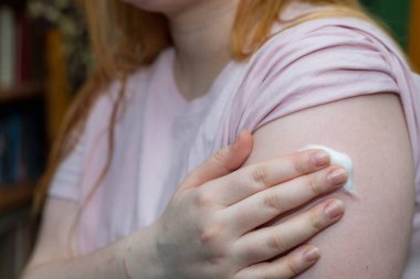 Bir kadın, koronavirüs enfeksiyonuna karşı aşılandıktan sonra omzunda bir post taşır..