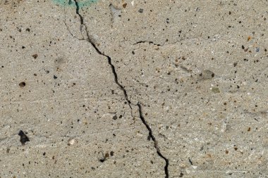 Çatlak beton bir temel tabakasının pürüzlü dokulu yüzeyi.