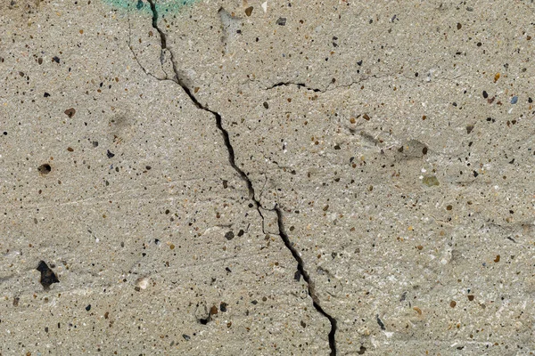 Çatlak beton bir temel tabakasının pürüzlü dokulu yüzeyi.