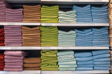 Bir rafta yığınla havlu var. Kişisel hijyen için tekstil ürünleri sergisi. Arkaplan