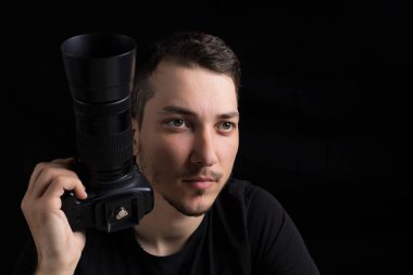 Siyah elbiseli, siyah elbiseli genç adam düz görünüyor, siyah arka planda, sade bir anahtarla. Metin için kopyalama alanı