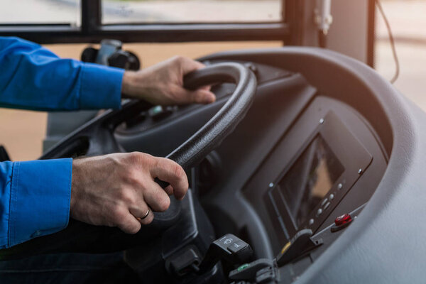 The drivers hands on the huge steering wheel of public transport. Trolleybus or bus driving. Background, toned