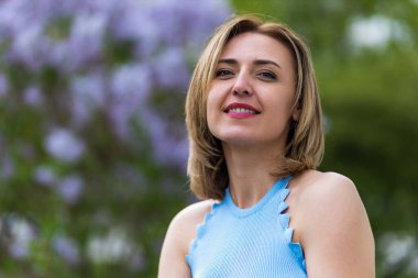 Otuz yaşından büyük mutlu bir kadının portresi çiçek açan ağaçların bulanık arka planında. Metin için kopyalama alanı