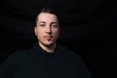 Siyah kapüşonlu genç ve yakışıklı bir adamın sade portresi.