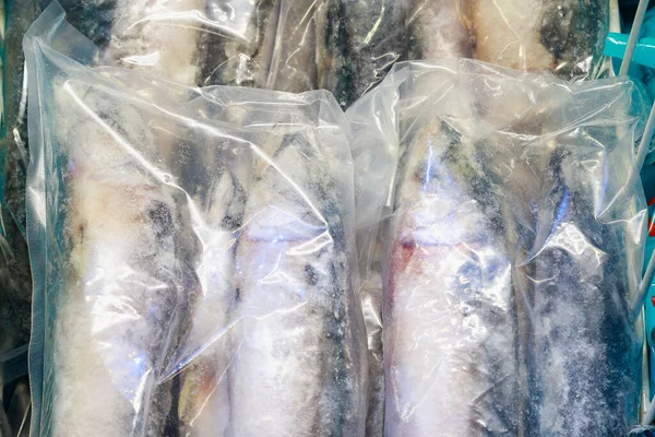 Plastic package with frozen fish products. Goods in the freezer of the store fridge. Close-up background. Seafood department in the market.