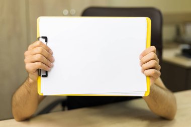 Elinde boş bir A4 kağıdıyla tablet. Tasarım için kopyalama alanı veya maketi olan soyut arkaplan.