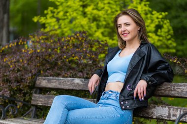 Otuz küsur yaşında bir kadının portresi. Parkta bir bankta dinleniyor. Metin için alanı kopyala.