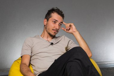 Elinde lavalier mikrofon olan bir blog yazarı çantaya oturur. Düşüncenin ve derin düşüncenin duygusu. Kopyalama alanı için bulanık arkaplan ile seçmeli odak.