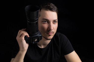 Siyah elbiseli, siyah elbiseli genç adam düz görünüyor, siyah arka planda, sade bir anahtarla. Metin için kopyalama alanı