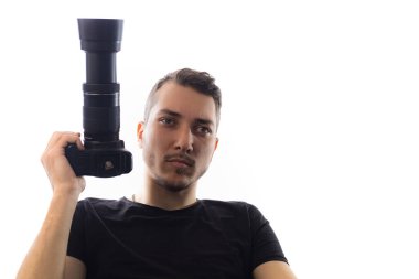 Kameralı yakışıklı bir genç adam, gözlere özen gösteriyor. Beyaz arkaplanda bir portre.