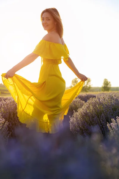 黄色のドレスのリラックスした美しいとかなり若い女性と日没のラベンダー畑で散歩を楽しんで トーン — ストック写真