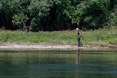 Metal detektörü ve nehir kenarında küreği olan bir adam. 28 Haziran 2021 Otaci Moldova. İllüstrasyon Editörü.