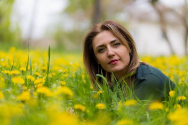 Karahindiba çiçekleri açarken bir şehir parkında genç bir kadın. Sarı neşeli şimşek konsepti. Mutluluk ve özgürlüğün sembolü