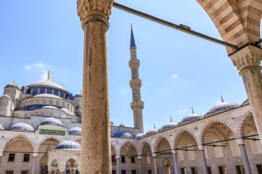 Blue mosque courtyard view with majestic minaret and archways under clear sky. August 12, 2025 Istanbul Turkey.