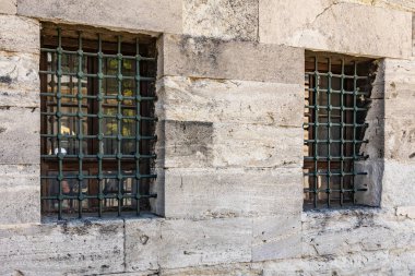 Stone building with barred windows reflecting historical architecture elements.