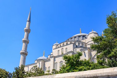 Majestic mosque minaret and dome against clear blue sky.