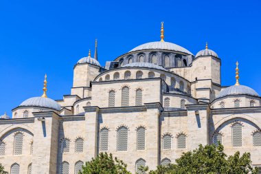 Architectural marvel: ottoman era mosque with domes and blue sky backdrop.
