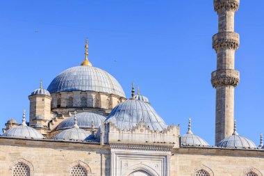 Ottoman architecture: domes and minaret of historic mosque against clear blue sky.