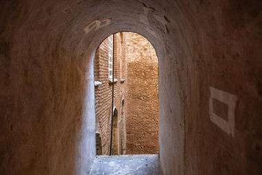 Historic brick alleyway with curved archway and weathered walls.