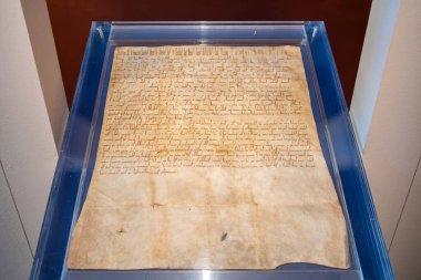 Ancient parchment document on display in blue-framed glass case.. March 22, 2025, Kutna Hora, Czech Republic.