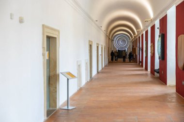 Arched hallway with red and white walls leading to artwork display.. March 22, 2025, Kutna Hora, Czech Republic.