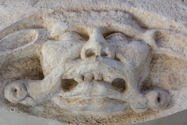 Stone gargoyle face with wild expression carved in relief.. March 22, 2025, Kutna Hora, Czech Republic.