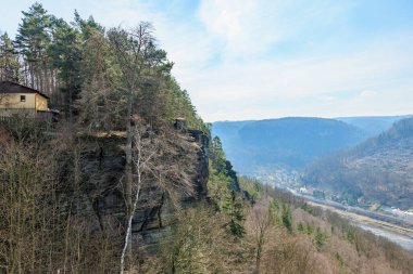 Scenic cliffside view of forest and river valley in winter landscape.