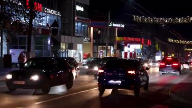 Akşam trafiği, Noel ışıkları ve aydınlatmalarla süslenmiş arabalarla dolu. 19 Aralık 2024 Balti Moldova.