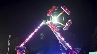 Parlak neon eğlence salıncakları Noel tatilleri ve yeni yıl kutlamaları sırasında gece boyunca şenlik parkında hareket ediyor. 20 Aralık 2024 Balti Moldova.