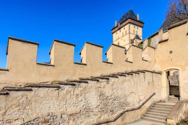 Historic medieval castle with stone walls and tower under clear blue sky.