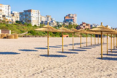 Saman şemsiyeli güneşli sahil ve kıyı binaları.
