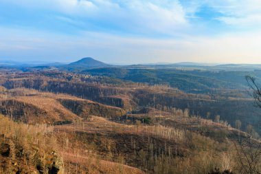 Scenic view of rolling hills and forested landscape under blue sky.