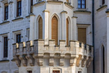 Stone balcony and arched windows on historic european castle facade.