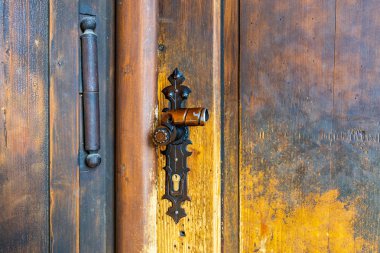 Rustic wooden door with vintage metal handle and lock close-up.