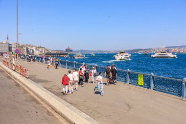 İnsanlar mavi rıhtımda güneşli bir günün tadını çıkarıyorlar. Tekneleri ve şehir manzarası olan. 12 Ağustos 2025 İstanbul Türkiye.