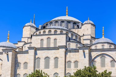 Açık mavi gökyüzüne karşı kubbeleri ve minareleri olan tarihi cami..