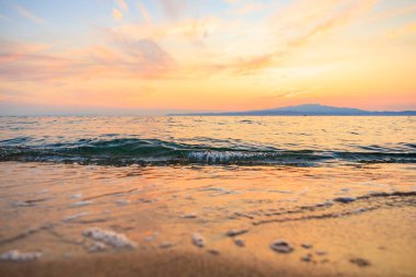 Okyanus sakin ve gökyüzü güzel turuncu bir renktir. Su gökyüzünü yansıtıyor. Huzurlu ve huzurlu bir atmosfer yaratıyor.