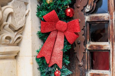 Kırsal ahşap pencereli yeşil çelenk ve süslü kırmızı fiyonk..