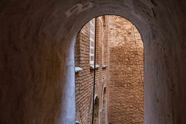 Kemerli girişi ve yıpranmış duvarları olan antik tuğla mimari tüneli..