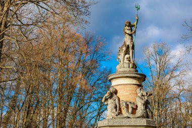Sonbahar parkında heykel ve mavi gökyüzü olan Neptün çeşmesi. 17 Mart 2025, Konopiste Şatosu, Çek Cumhuriyeti.