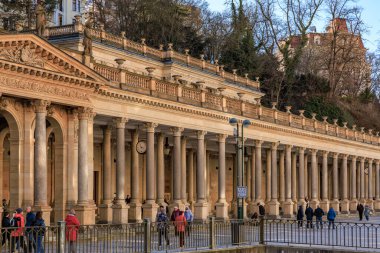 Karlovy 'deki tarihi sütunlar, büyük mimarinin önünden geçen ziyaretçilerle değişkenlik gösteriyor. 18 Mart 2025, Karlovy Vary, Çek Cumhuriyeti.