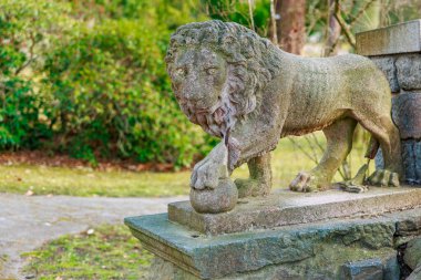 Parktaki taş aslan heykeli antik mimari elementlerle birlikte. 17 Mart 2025, Konopiste Şatosu, Çek Cumhuriyeti.